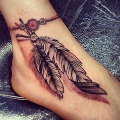 a foot with a feather and cross tattoo on it