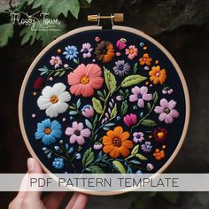 a person holding up a colorful floral embroidery pattern