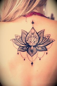 the back of a woman's shoulder with a lotus tattoo on her left side