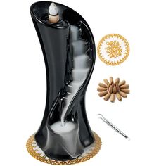 a black vase with gold accents and other items around it on a white surface next to a pair of scissors