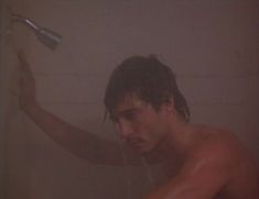 a shirtless man is holding a shower head