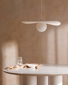 a white table with two wine glasses on it and a light fixture hanging from the ceiling