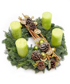 a wreath made out of green apples and pine cones with candles on top, surrounded by greenery