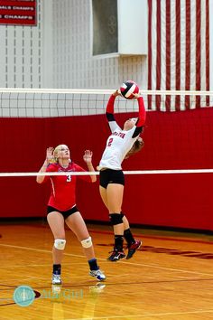 two women playing volleyball in a gym