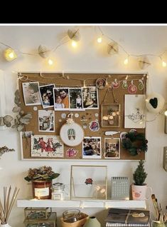 a desk with many pictures on the wall and lights strung above it, along with other office supplies