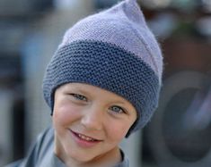 a young boy wearing a knitted hat and smiling