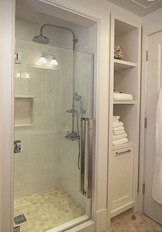 a walk in shower sitting inside of a bathroom next to a white towel dispenser