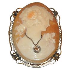 This exquisite Victorian Cameo surrounded with 14K yellow gold filigree is accented with a .10 carat diamond pendant delicately hanging on necklace within the cameo. This wonderful cameo can be worn either as a brooch or pendant if desired. The height measures 1 3/4 inches, width measures 1 3/8 inches, with a depth measuring 5/8 inch. Victorian Pendant Necklace, Crocheted Clothes, Victorian Cameo, Art Deco Filigree, Victorian Pendants, Ultimate Christmas, Cameo Jewelry, Antique Pendant, Antique Brooches