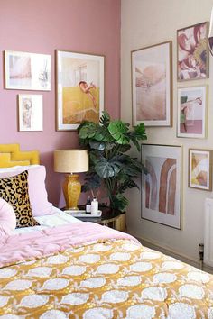 a bedroom with pink walls and pictures on the wall, including a yellow headboard