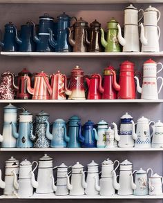 a shelf filled with lots of different colored coffee pots