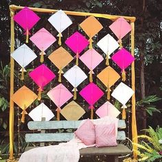 a wooden bench sitting in front of a colorful wall hanging from it's sides