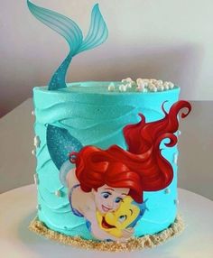 the little mermaid cake is decorated with blue icing and has an image of ariel on it