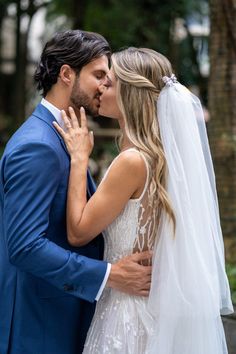 a bride and groom kissing each other outside