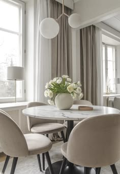 a dining room table with chairs and a vase filled with flowers on top of it