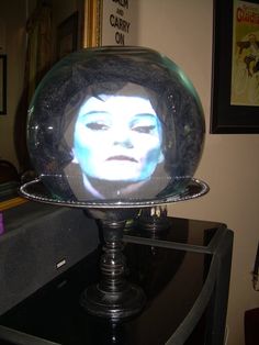 a woman's face is projected in a glass bowl on top of a table