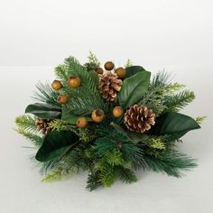 a bouquet of pine cones and greenery on a white surface