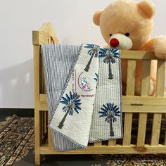 a teddy bear sitting on top of a wooden crib next to two folded towels