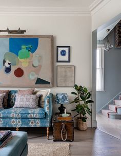 a living room with blue couches and paintings on the wall above them, along with other furniture