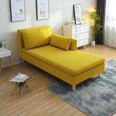 a yellow couch sitting on top of a wooden floor next to a white table and chair