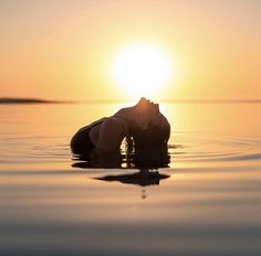 a person floating in the water at sunset with their head above the water's surface