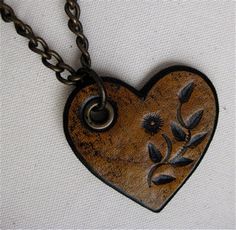 a heart shaped pendant with leaves on it