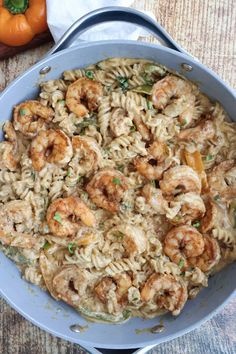 pasta with shrimp and parmesan cheese in a skillet on a wooden table