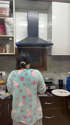 a woman standing in front of a stove top oven