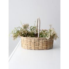 a wicker basket with flowers in it sitting on a countertop next to a white wall