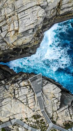 an aerial view of the ocean and rocky coastline with stairs leading up to it's entrance