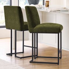 two green chairs sitting next to each other on a wooden floor in front of a window