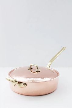 a pink pan with gold handles on a white surface