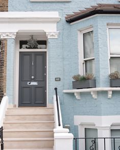 a blue house with white trim and two windows on the front door is seen in this image