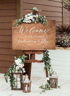 a welcome sign with flowers and greenery on it