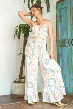 Effortlessly chic, embrace a bohemian vibe in our Circle in the Sand Wide Leg Jumpsuit. The vibrant print and cut out details elevate this piece, while the plunging V-neckline and open back add a touch of allure. Adjustable halter tie, smocking elastic waistband, and side pockets provide both comfort and style. The perfect addition to your summer wardrobe. Summer V-neck Jumpsuit With Tie Back, Beach Printed Patterned Jumpsuits And Rompers, V-neck Beachwear Jumpsuits And Rompers For Poolside, Bohemian Printed V-neck Jumpsuits And Rompers, Beach Patterned Jumpsuits And Rompers, Fitted Bohemian Jumpsuits And Rompers For Beach, Summer Vacation Hippie Jumpsuits And Rompers, Hippie Style Summer Vacation Jumpsuits And Rompers, Hippie Summer Jumpsuits And Rompers For Vacation