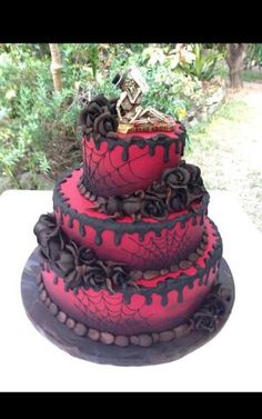 a three tiered cake with red and black icing on the bottom, topped with a skeleton figurine