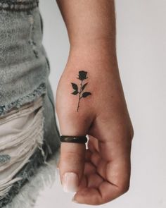 a woman's hand with a small black rose tattoo on her left thumb and wrist