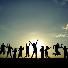 a group of people standing next to each other on top of a field at sunset