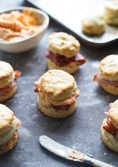 biscuits with ham and cheese on them next to a bowl of potato chips