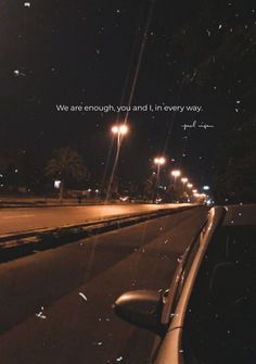 a car is parked on the side of the road at night with an inspirational quote above it