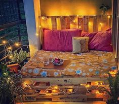 a bed made out of wooden pallets with lights on the headboard and pillows