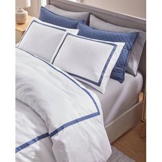 a white bed with blue trim and pillows