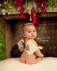 a baby wearing a tiara sitting on a fur rug in front of a fireplace