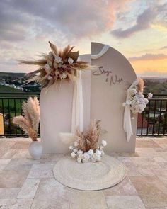 an outdoor ceremony setup with flowers and pamolite on the ground in front of a sunset sky