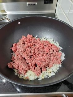 ground beef and onions being cooked in a frying pan on the kitchen stove top