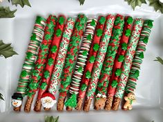 christmas crackers and candy canes are arranged on a platter with holly leaves