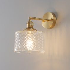 a wall light with a glass shade hanging from it's side against a white wall