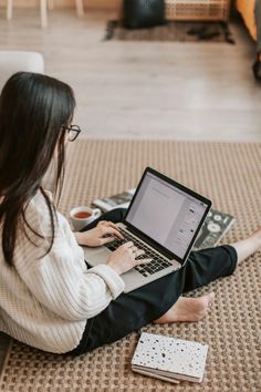 a woman sitting on the floor using a laptop computer