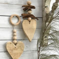 two wooden heart shaped ornaments hanging on a white wood wall next to a tree branch