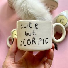 someone holding up a coffee mug with writing on it that says cute but scorpio