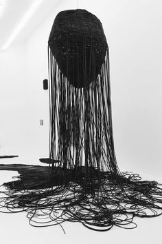 an artistic sculpture made out of wires on the floor in front of a white wall